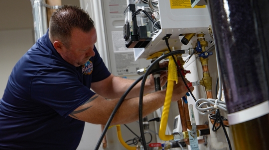 All City Plumbing tech working on tankless water heater