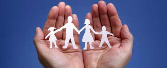 Person holding paper dolls that represent a family