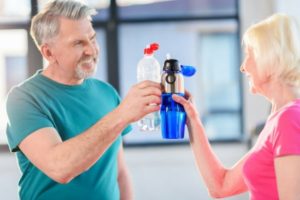 two people clinking their water bottles in cheers 