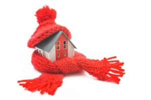 Small toy house wrapped up in a winter scarf and hat