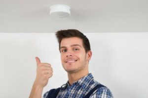 Man giving a thumbs up after checking his smoke detector