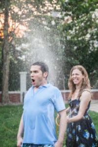 woman spraying a man with a hose