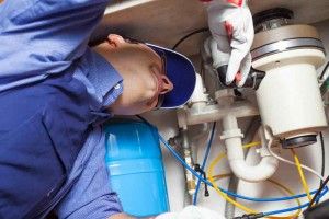 Plumber working on a garbage disposal under the sink