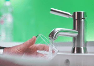 Person filling a glass with water from the faucet