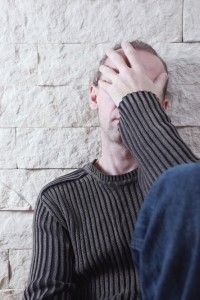 Man sitting on the flood covering his face