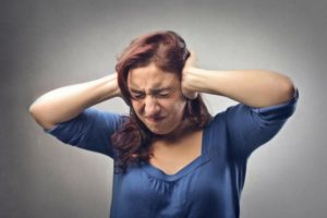 Woman holding her hands over her ears