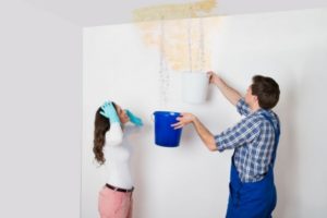 two people catching water as it leaks from the ceiling