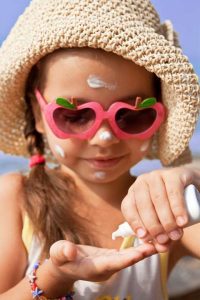 Little girl applying sunscreen to her face