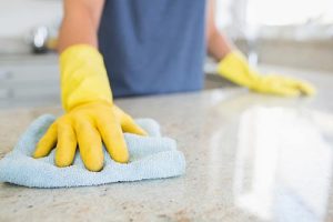 Person wearing yellow rubber gloves cleaning the floor