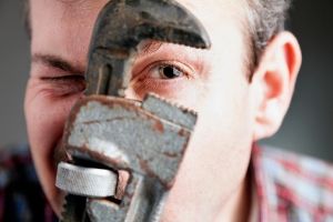 Man holding a wrench to his face