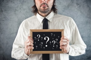 Man holding chalkboard with question marks on it